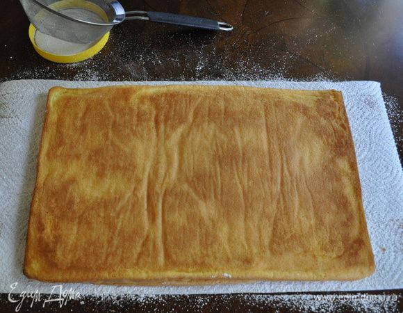 Перевернуть бисквит на полотенце и аккуратно снять пергамент. 