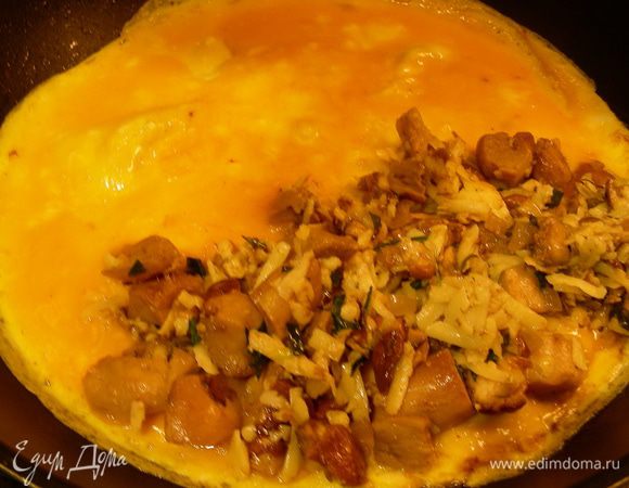 Когда омлет уже довольно хорошо схватился, выкладываем на одну половину нашу начинку.