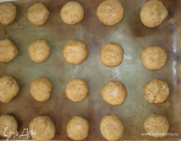 Накрыть миску пищевой пленкой и дать тесту немного остыть. Противень застилить пергаментной бумагой. Скатать шарики и выложить их на противень на достаточном расстоянии друг от друга. Расплющить шарики рукой до кружочков.