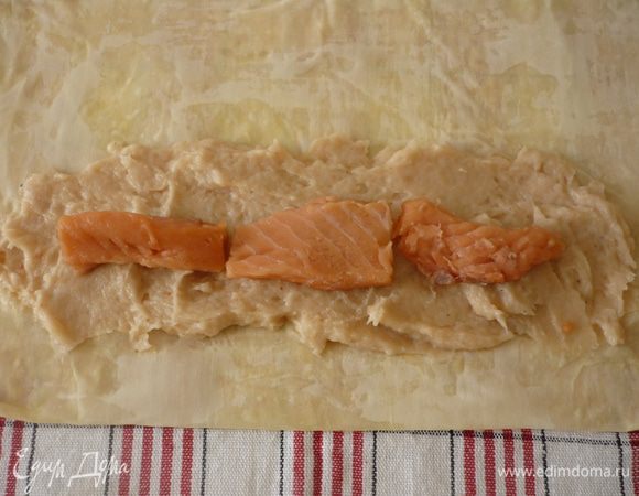 Взять листочек теста (остальные сразу накрыть), выложить на полотенце, промазать растопленным маслом, сложить в длину пополам. Далее по очереди берём ещё два листочка, каждый смазываем маслом и складываем. На длинную сторону получившейся стопочки из листов теста выкладываем фарш из белой рыбы, на него кусочки форели и заворачиваем в рулетик.