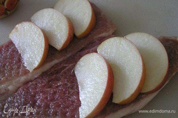 Яблоки вымыть, нарезать тонкими ломтиками, сбрызнуть лимонным соком и выложить на мясо.