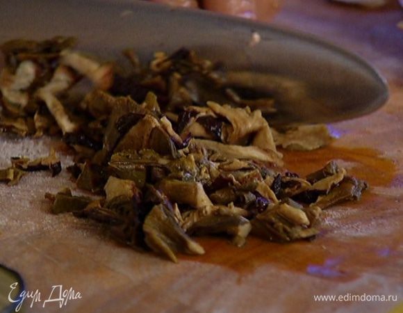 Замоченные грибы откинуть на дуршлаг, отжать и мелко порубить.