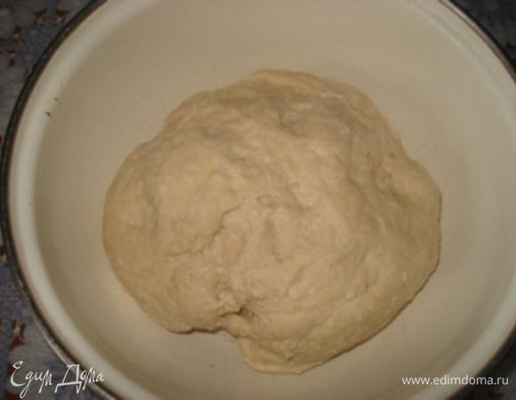 Перемешать ингредиенты сначала деревянной ложкой, а затем месить тесто руками 10-15 минут на доске. Сформировать из теста шар, тобмазать маслом растительным и поставить подходить в теплое место на 1-2 часа.

