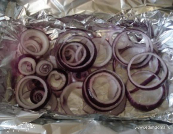 Лук нарезать кольцами. Форму для запекания выложить фольгой и первым слоем выложить лук, затем на лук положить стейки и все залить сливочным маринадом.