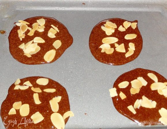 Противень смажьте тонко сливочным маслом. Столовой ложкой выливайте тесто небольшими порциями на расстоянии друг от друга(чтобы не слились), присыпьте миндальными хлопьями.