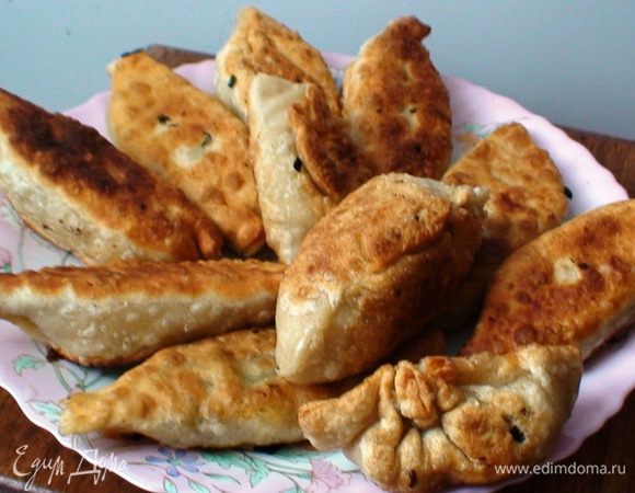 Месим тесто. Из муки и воды замешиваем тесто, кладем его отдыхать на 15 минут, присыпав мукой. Когда уже тесто отдохнуло раскатываем в пласт в виде круглой лепешки толщиной приблизительно 2 мм. 
Готовим начинку. Яйца отвариваем, чистим и нарезаем кусочками. Зеленый лук и зелень нарезаем не сильно мелко. Лук обжариваем на сковороде немного подсолить. Все это смешать и посолить и поперчить по вкусу. 
Далее нашу начинку класть в лепешку по 1 ст. л. Края лепешек соединить как на вареники и немного приплюснуть. Обжариваем в масле. Украшаем и подаем на стол теплыми. Приятного аппетита!