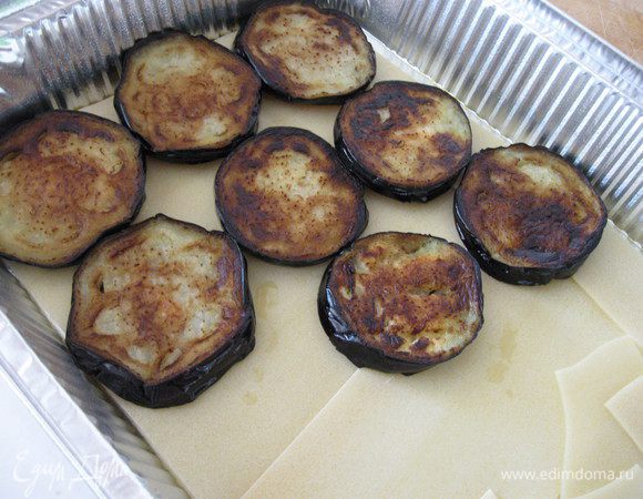 На дно смазанной маслом формы  выложить листы лазаньи, сверху кружочки баклажан


