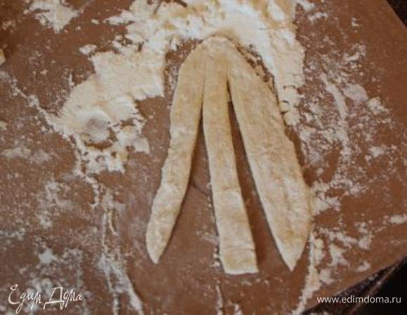 Тесто сктываем в жгутик и нарезаем небольшими кусочками. Каждый кусочек раскатываем в продолговатую лепешку, которыу нарезаем на три полоски (не до конца!)