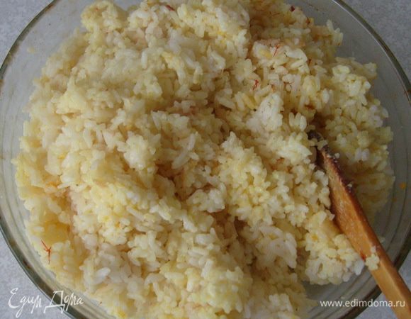 Отварить рис в подсоленной воде (около 1-1,2 литров) до тех пор, пока рис не впитает в себя всю жидкость и образует вязкую крахмальную массу. Снять с плиты и дать слегка остыть.
В чуть остывший рис ввести желтки, разведённый порошок шафрана, масло сливочное и тертый сыр. Хорошо размешать до однородной массы и выложить на плоскую тарелку до полного остывания. (Если видите, что рисовая масса не такая вязкая, как нужна для формирования шариков, добавьте 1 ст.л. крахмала)