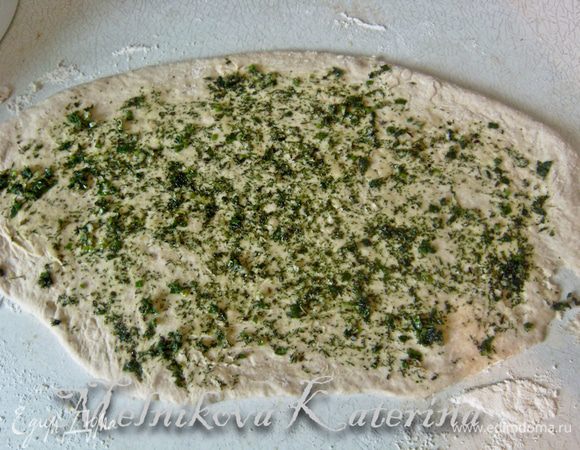 Тесто разделить на две примерно равные части. Берем одну часть, раскатываем в овал. На тесто выкладываем половину начинки и ножом аккуратно разравниваем по всей поверхности (начинки на самом деле не очень много, на одну часть получается примерно 0,5 столовой ложки, поэтому распределить ее равномерно удобнее ножом). 