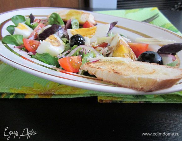 Салат вымыть, высушить и выложить на тарелку.
Помидоры черри разрезать на четвертинки и разложить на листья салата.
Также поступаем и с яйцом, разрезать на четвертинки и выложить на тарелку с салатам. 
Добавляем маслины, базилик и красный лук, нарезанный очень тонко. Добавляем немного пармезана. Если есть необходимость, посолить и поперчить.
Готовый салат сбрызнуть бальзамическим уксусом и полить хорошим оливковым маслом. 
Два кусочка багета подсушить и положить на тарелку с салатом. Можно наслаждаться легким ужином. Приятного аппетита!