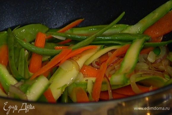 Добавить кабачок, морковь и спаржу. Обжаривать минуту, затем выложить в сковороду фасоль и горох.
