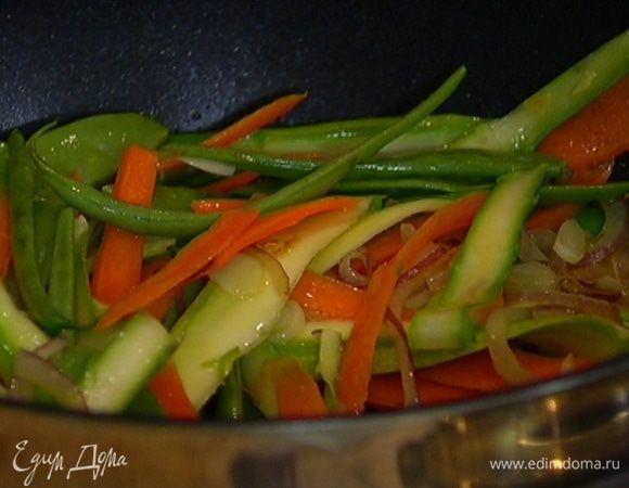 Добавить кабачок, морковь и спаржу. Обжаривать минуту, затем выложить в сковороду фасоль и горох.