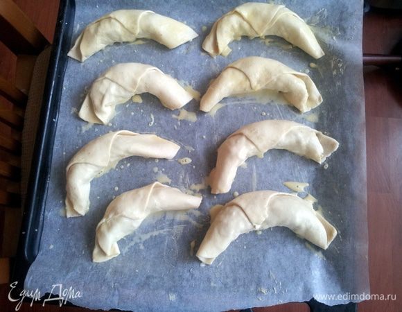 Придать пирожкам форму круассанов.
Выложить на противень. Смазать круассаны желтком и выпекать в заранее нагретой духовке при температуре 200С в течении 15 минут, до золотистой корочки.