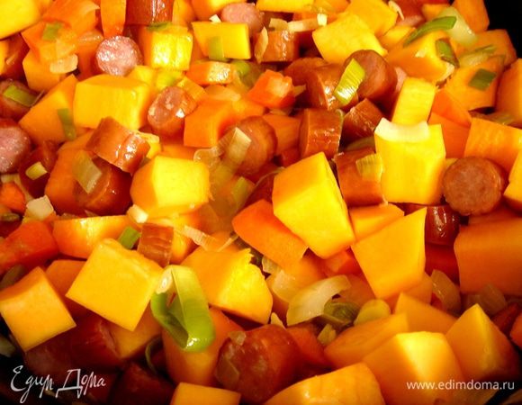 Все овощи нарезать кубиками. В глубоком сотейнике обжарить на растительном масле два вида лука и чеснок,затем-кусочки моркови и после тыквы. Готовить до полуготовности тыквы. Добавить нарезанные на кусочки охотничьи колбаски и курицу, а затем немного растолчённые в ступке специи; тушить 5-7 минут.