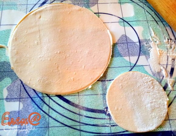 Слоеное тесто раскатать в тонкий пласт. Вырезать из теста два круга. Один такого же диаметра, как кружок сыра, второй в два раза больше.