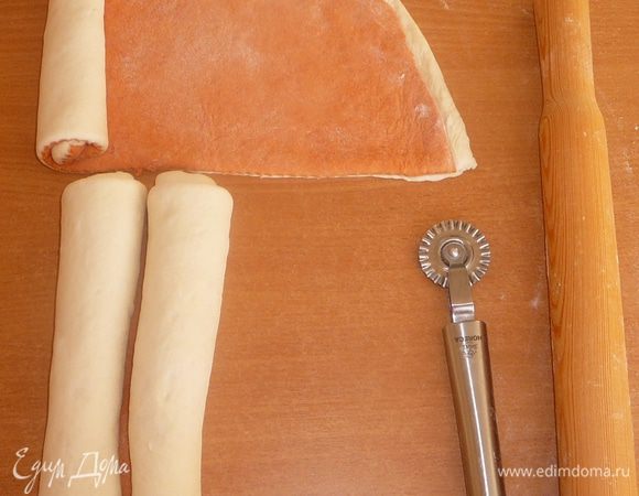 Раскатываем два коржа, потом красный корж кладем на белый, разрезам оба коржа на 2 равные части. Формируем рулет, скатывая тесто от краев к центру одновременно.