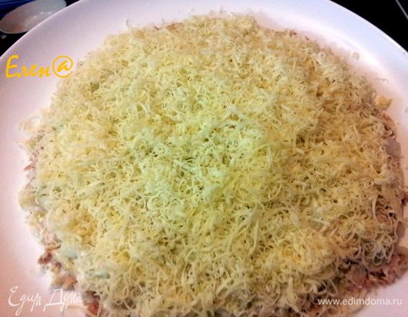 Репчатый лук мелко нарезать и также выложить, сверху посыпать тертым на мелкой терке сыром. Достать масло из морозилки, и натереть на терке над салатом, так чтобы стружки масла покрыли тонким слоем салат. Сверху натереть на мелкой терке желток.