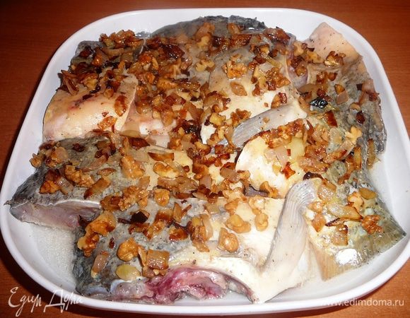 Затем выкладываем рыбу в форму для запекания. Сверху выкладываем обжареный лук с орехами.