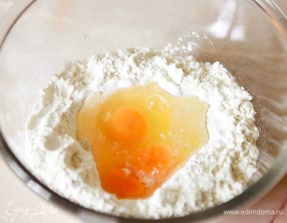 Делаем тесто: просейте муку в миску. Сделайте углубление и вбейте яйца.
