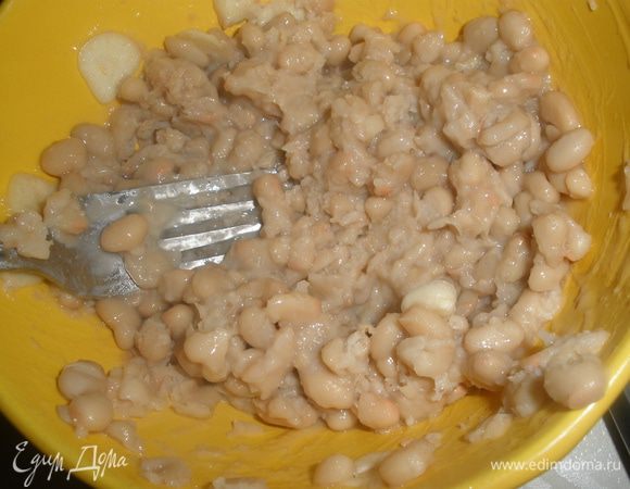 Смешать фасоль с чесноком. Немного помять вилкой, но не до состояния пюре!