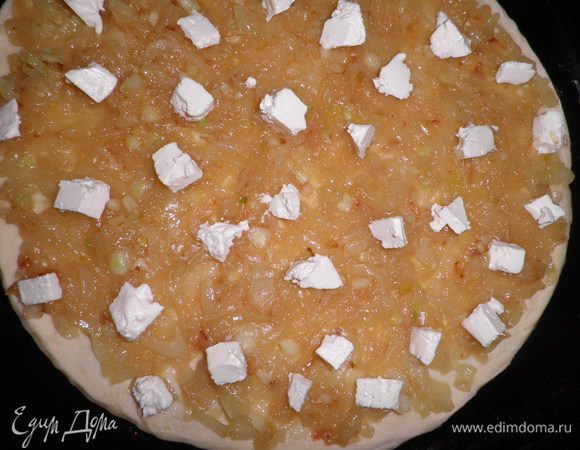 Тесто раскатать в лепёшку и поместить на противень,смазанный маслом.Сверху выложить лук и присыпать раскрошенным сыром.

