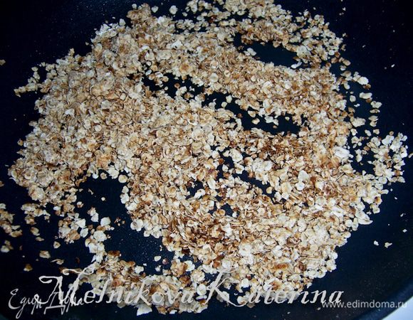 Приготовить начинку. Для этого на раскаленную сковороду положить сливочное масло и овсяные хлопья. Поджарить их до золотистого цвета, они станут хрустящими как чипсы или орешки. 