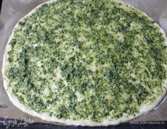 Выкладываем тесто на хорошенько подпылённую мукой поверхность и кулаками растягиваем его до нужного размера и формы, толщина должна быть примерно 0,3-0,5 см. 
 Перекладываем тесто на лист (я кладу пекарскую бумагу и присыпаю мукой), края при помощи кисточки смазываем оливковым маслом с паприкой, всю поверхность - соусом песто, приготовленным по рецепту: http://www.edimdoma.ru/retsepty/40731-sous-pesto, не доходя до края 1 см. Оставим в тёплом месте подготовленную пиццу, пока нарезаем начинку. Я ставлю минут на 5-7 в духовку, нагретую до 50 гр. Затем пиццу убираю и нагреваю духовку до 250 гр.