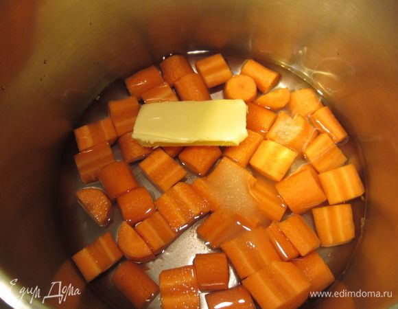 Положите морковь в сотейник. Залейте морковь водой, чтобы она не до конца прикрывала ее. Положите туда половину масла, сахар и соль. Поставьте на средний огонь.