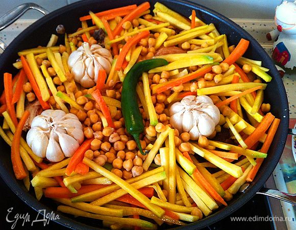 Включаем панель под Вок на 9 (максимум). Ждем пару минут. Добавляем в Вок нарезанный кубиками жир, обжариваем, шкварки вытаскиваем (либо съедаем с луком, лепешкой и солью, либо выбрасываем). Наливаем в казан масло и прогреваем его пару минут (нужно сделать смесь масел, тогда уже в готовом блюде жир не будет застывать). Добавляем в Вок маленькую очищенную луковицу (целиком) и жарим ее до черноты (луковица придаст особый запах и цвет маслу), обжаренную луковицу вытаскиваем и выбрасываем. Далее нужно обжарить 2 крупных куска курдючного сала, не сильно со всех сторон, буквально пол минуты, вытащить и отложить на тарелку. Далее нужно хорошо обжарить косточку и ребрышки, вытащить и отложить на тарелку, а затем в Вок добавляем мясо и так же прожариваем(перед тем как добавить мясо, лучше немного дополнительно прогреть масло, что бы куски мяса попадая в горячее масло мгновенно порывались корочкой не давая вытекать из них соку). Не вынимая мяса из Вока, добавляем нашинкованный лук и обжариваем его с мясом, пока лук не станет золотистого цвета (лук в плове обязателен, он придает маслу вкус и цвет, в готовом блюде лука невидно). После того как все обжарено, к мясу и луку добавляем сверху косточку, курдюк и ребрышки отложенные ранее. Добавляем кинзу крупного помола (кориандр), черный перец горошком и столовую ложку соли с горочкой. Сверху засыпаем нарезанной соломкой морковью, разравниваем и вливаем в Вок пол литра холодной воды (Часто морковь выращенная в России не выдерживает долгой тепловой обработки при приготовлении плова и теряет форму развариваясь в кашу, здесь мы убираем процесс обжаривания и предотвращаем это). Воды должно быть меньше содержимого казана. После закипания морковь должна готовиться на пару. Сливаем воду с гороха и засыпаем его сверху на морковь (так же выкладываем на морковь чеснок и стручковый перец ). 