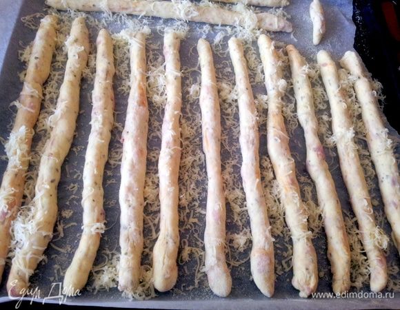 И скатать каждую в тонкую колбаску.
Противень смазать маслом и присыпать манной крупой.
Колбаски выложить на противень, присыпать оставшимся сыром и выпекать в духовке при температуре 200С 10-15 минут.