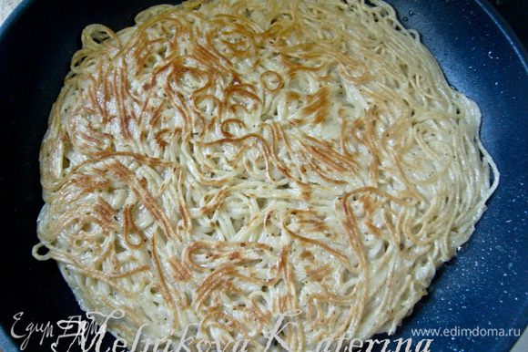 На сковороде разогреть оливковое масло. Выложить половину спагетти, разровнять, поджарить до золотистой корочки (около 5 минут). Используя лопатку, перевернуть основу и поджарить другую сторону. Аналогично поступить и со второй частью спагетти.