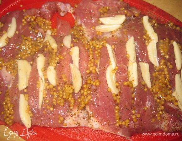 На мясном пласте делаем продольные разрезы, солим, перчим, посыпаем смесью специй для мяса с обеих сторон, и обмазываем зернами горчицы. В продольные разрезы вставляем пластины чеснока.Оставляем мариноваться на 1 час.
