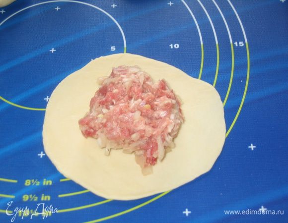 От теста отрезать краешек, скатать колбаску и нарезать на небольшие порции. Каждую порцию теста раскатать в круг (примерно 15 см диаметром). В центр положить 2 ложки с горкой начинки