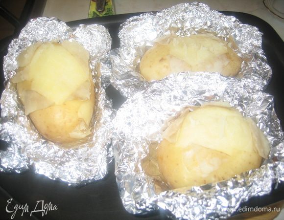 За 20 минут до окончания запекания надо раскрыть фольгу, надрезать картофель крестиком и продолжить запекать до полной готовности и подрумянивания