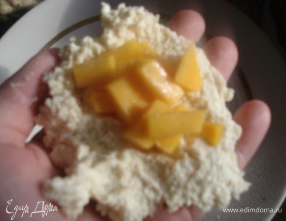 Дать тесту постоять 15 минут. Этого времени достаточно, чтобы набухла манная крупа. В это время 1/2 манго очистить и порезать кубиками. Положить немного теста на ладонь, в центр выложить 1 ч.л. нарезанного манго.

