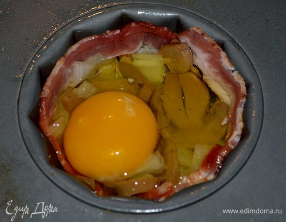 Выложить обжаренный лук с грибами в гнезда.Сверху на каждое гнездо разбить яйцо.Поставить в духовку на 15-20мин.Или до легкой хрустящей корки бекона .