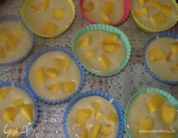 Смазать формы для маффинов маслом и разлить по ним тесто. Манго почистить, удалить косточку, а мякоть нарезать кубиками. Кусочки манго добавить в формочки с тестом.