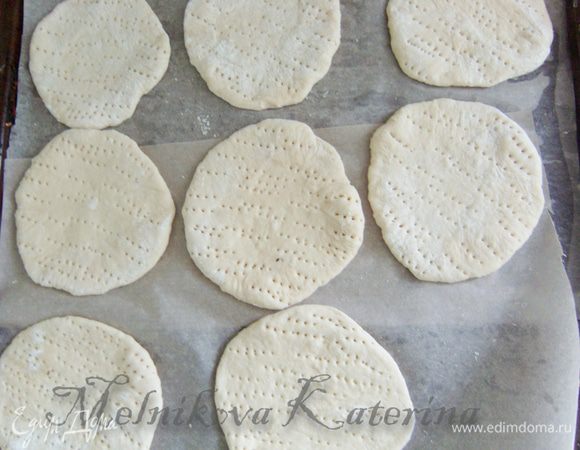 Раскатать каждую часть толщиной примерно в 0,5 см. Противень выстелить пекарской бумогой, смазать сливочным маслом. Выложить "лепешки", наколоть вилкой. Поставить в теплое и укромное место на 30-40 минут для подхода.