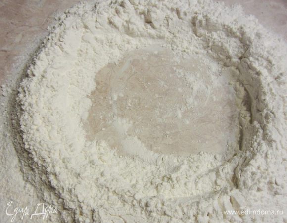 Сделайте посередине муки колодец, причем довольно большой - сантиметров 15 в диаметре. 