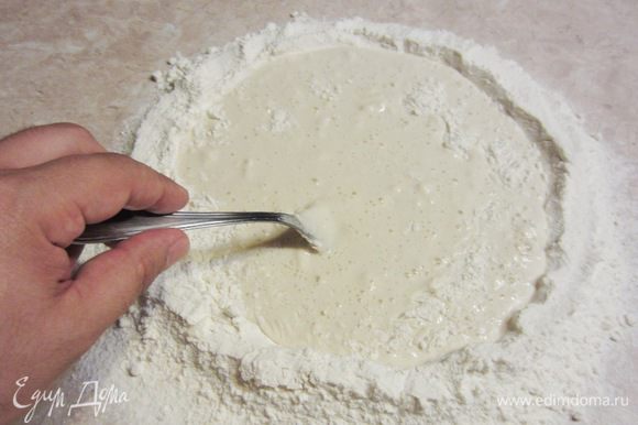 Начните вилкой замешивать тесто, понемногу забирая муку со стенок внутри колодца.