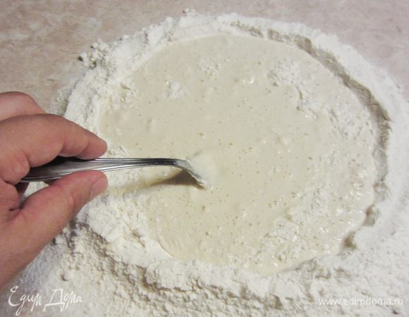 Начните вилкой замешивать тесто, понемногу забирая муку со стенок внутри колодца.