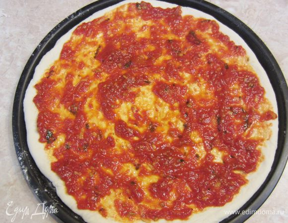 Выложите третью часть соуса посередине пиццы и распределите его так, чтобы по краям пиццы осталось свободное пространство около сантиметра.