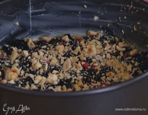 Разъемную форму для выпечки смазать оставшимся сливочным маслом, равномерно распределить половину теста, посыпать частью орехов, выложить варенье, а затем еще орехи (немного сохранить).