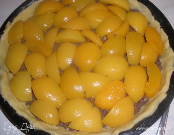 С персиков слить воду, обсушить их. Порезать на половинки и уложить на шоколад. 