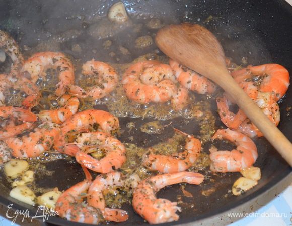 Разогреть в большой сковороде оливковое масло и обжарить на среднем огне чеснок. Выложить  к нему очищенные и размороженные креветки. Обжарить 2 минуты. 
