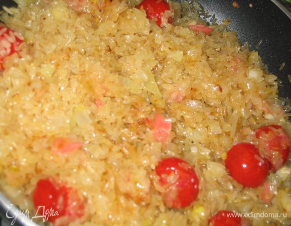 Добавить рис и шафран, все перемешать и держать 1 минуту, помешивая...осторожно, чтобы не раздавить помидорки
