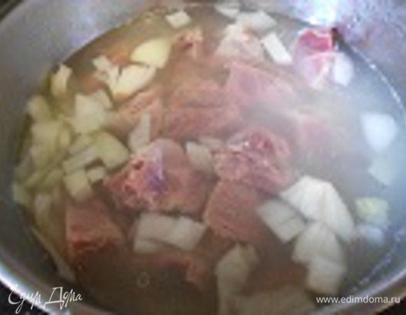 Мясо посолить, поперчить, выложить на лук и сразу налить 1.5 литра горячей воды. Воды должно быть больше примерно на ладонь. Довести до кипения, огонь убрать до среднего и тушить ровно 2 часа.
