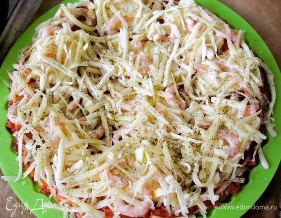 Испеченный корж смазать соусом, выложить моцареллу, креветки и посыпать твердым сыром.