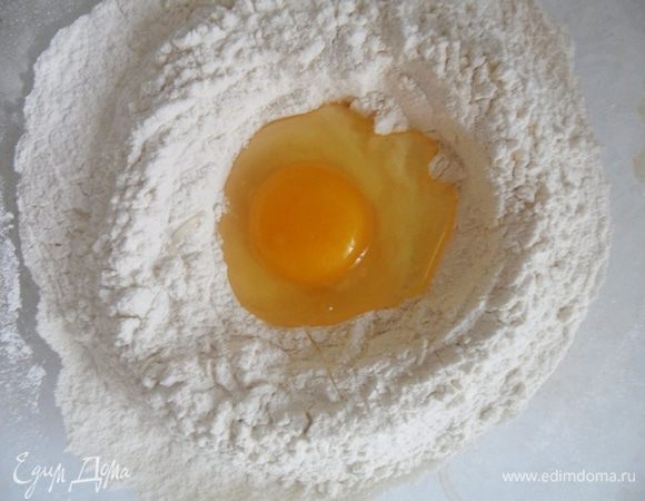  В глубокую миску высыпать 2 стакана муки,сделать в середине углубление и влить яйцо.